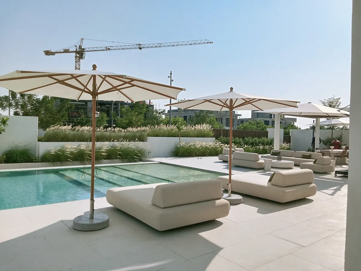 Piazza centre-pole umbrellas shading daybeds beside a pool in Jubail Island, Abu Dhabi
